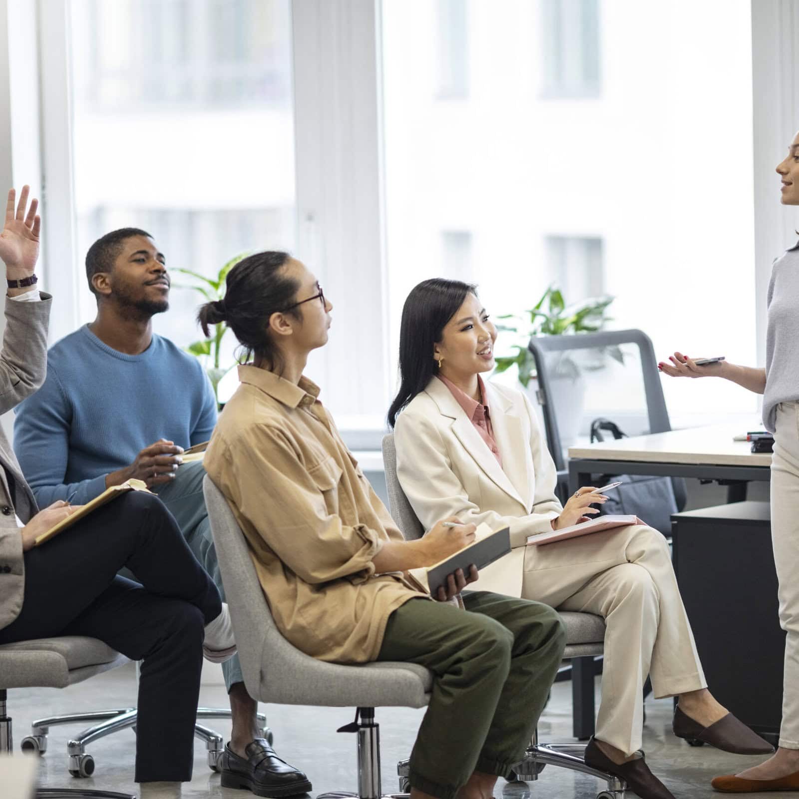 A group of business professionals in an office setting having a meeting going over how to support their teams better with coaching.