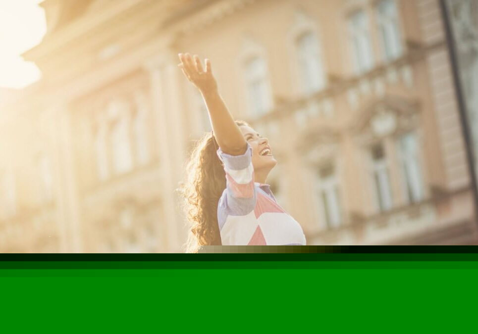 woman holding arms up in joy in front of a building