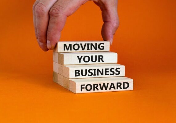 person stacking blocks that say Moving Your Business Forward