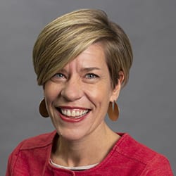 Carrie Abner headshot photo, smiling woman with short blond hair and red top