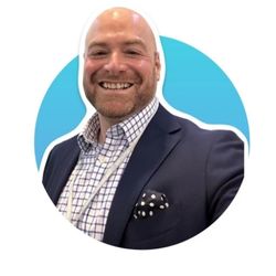 Terence Clarke PCC headshot photo, smiling man wearing white and blue button up shirt with dark blazer over popped out over a blue circle