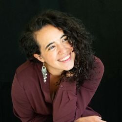 Lucie Coudret ACC headshot photo, woman with long dark hair and maroon shirt smiling