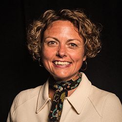 Alicia Hullinger headshot photo, smiling woman with short curly hair and a light colored top