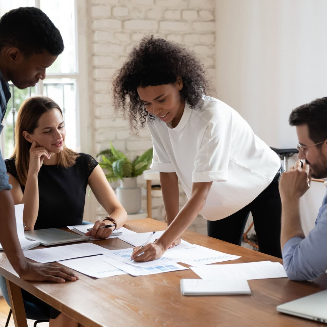 A group of professionals work together in an office reviewing several documents.