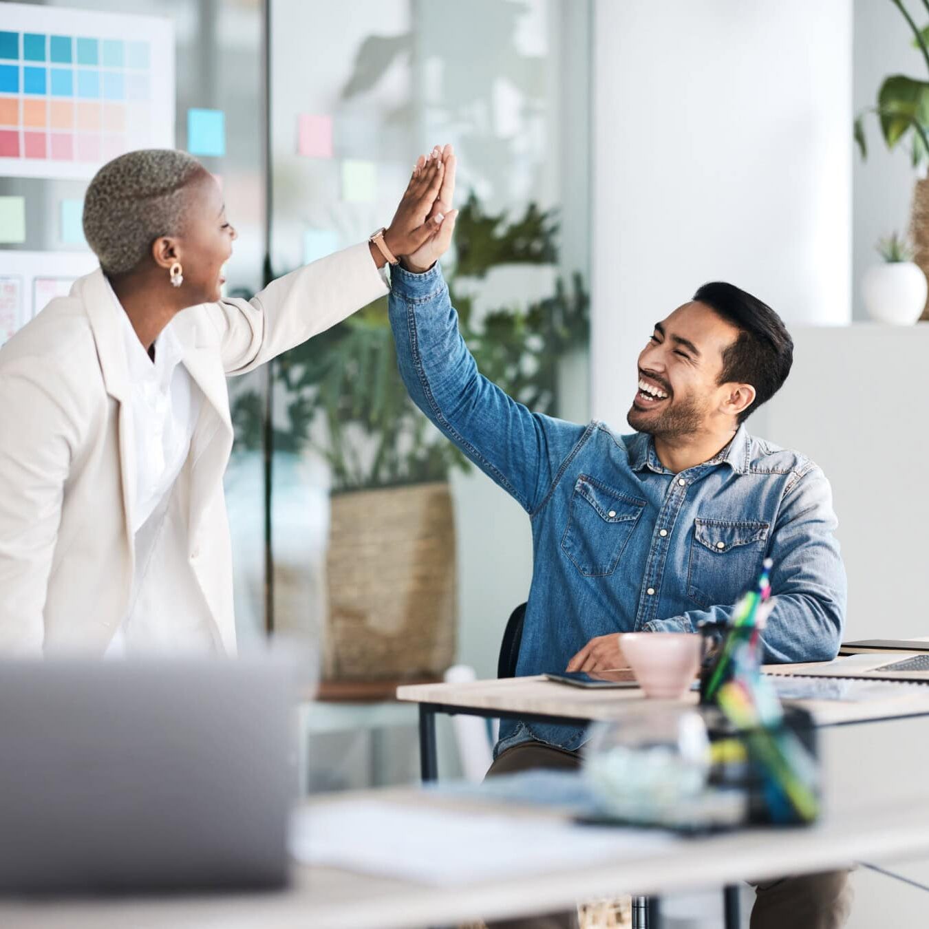 A man and a woman high five in an office setting.