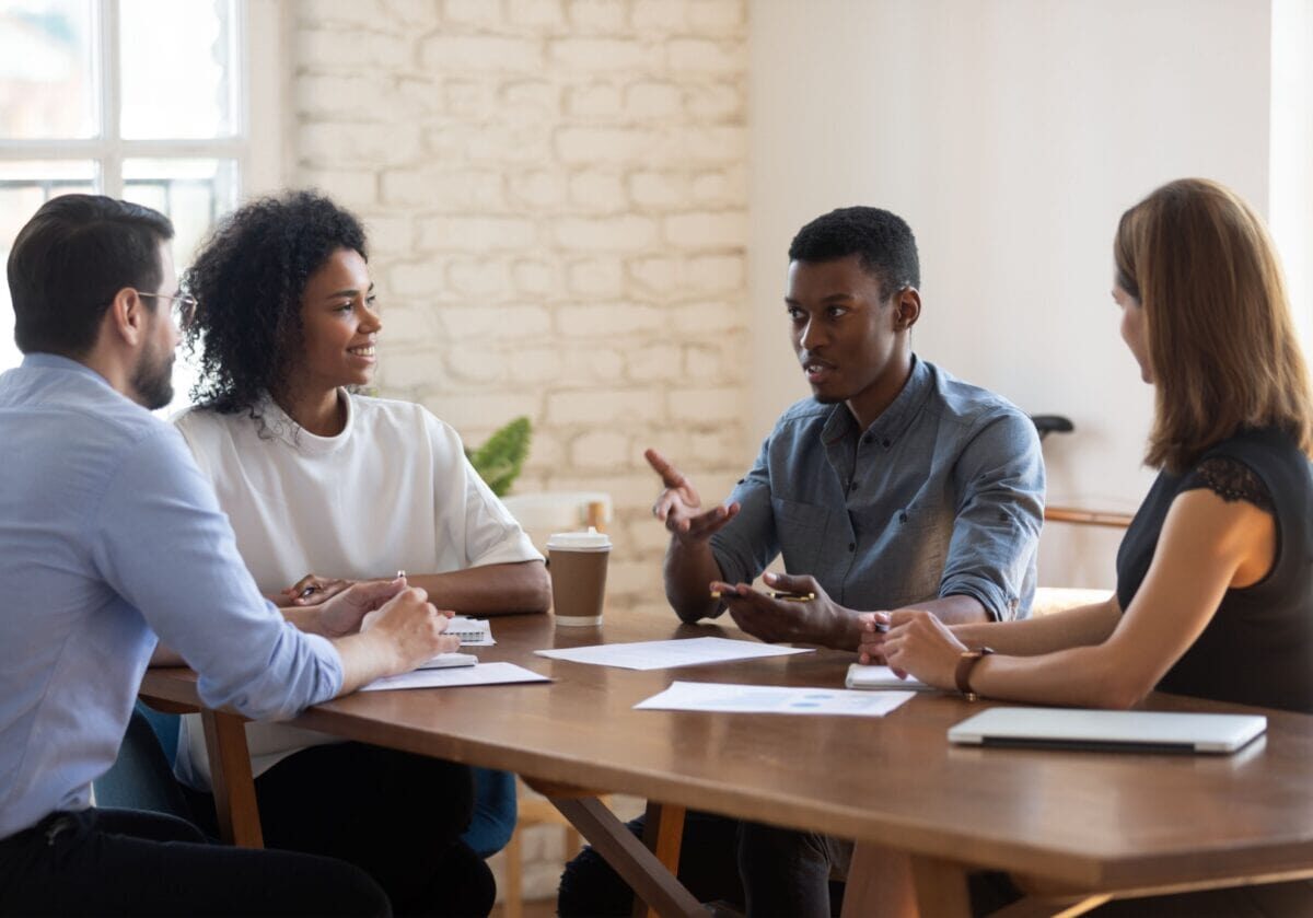 Four colleagues in a coaching session discussing ideas around a table.