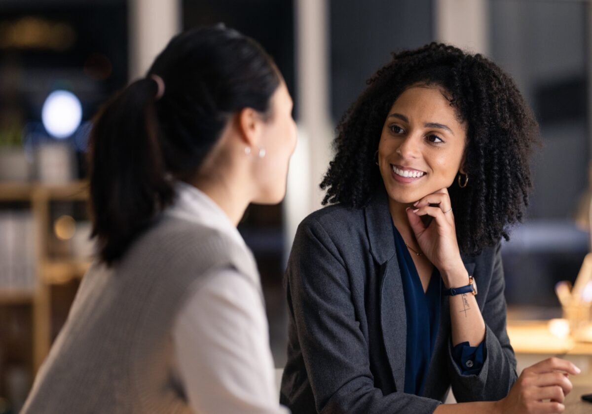 A professional coach listens attentively to a client during a one-on-one coaching conversation.