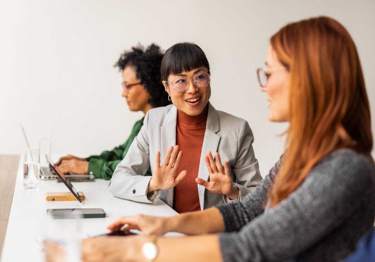 Three diverse women engaged in a business meeting at a conference table.