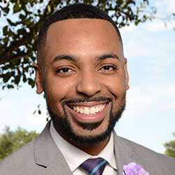 Josh Champion headshot photo, smiling man in suit outside