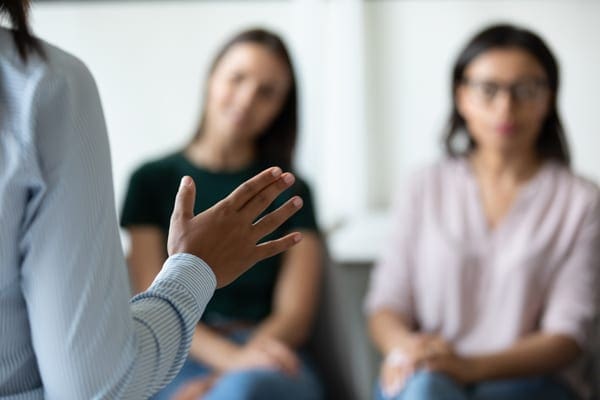 leader speaking to two seated women