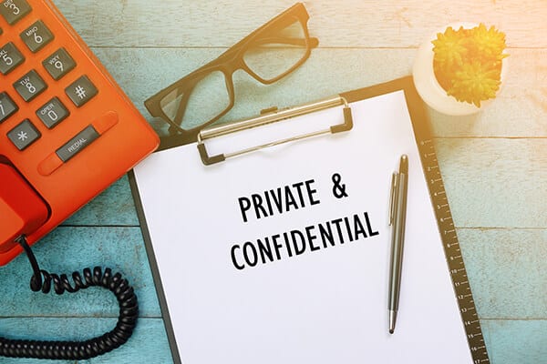private & confidential written on a paper on a clipboard next to a pair of glasses a phone and a small succulent on a table