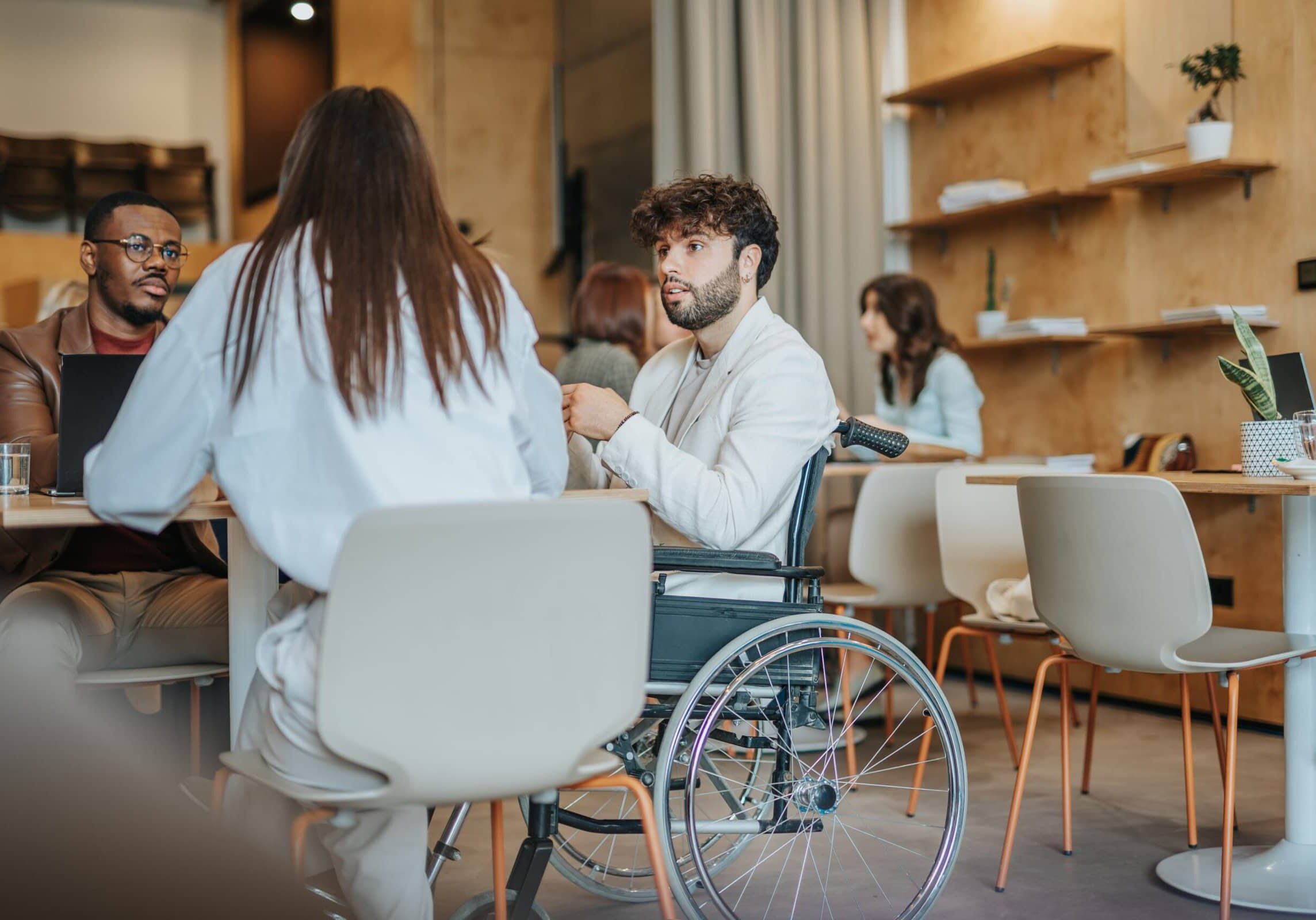 two people sitting in chairs at a table with a third in a wheel chair all in conversation